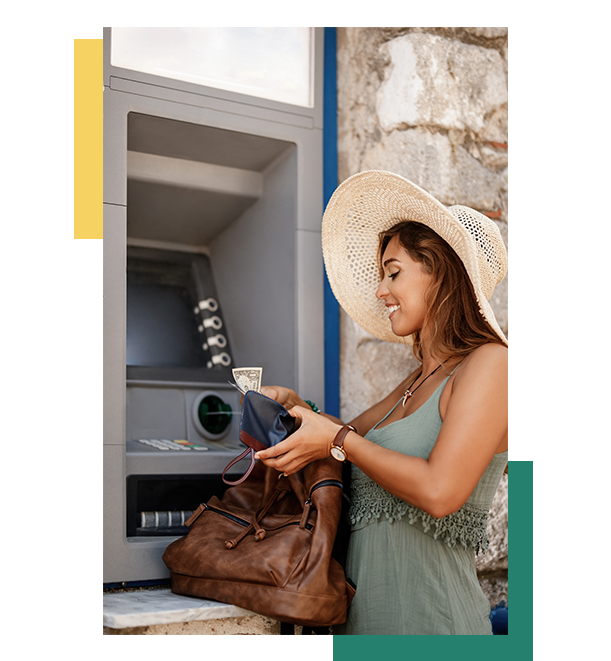Smiling woman withdrawing cash from ATM, placing dollar bill into wallet, wearing sun hat and summer dress outdoors