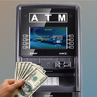 Hand holding cash in front of a black ATM machine screen showing welcome message for ATM machine sales.