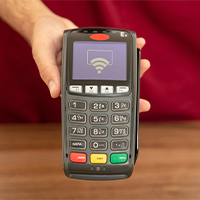 Hand holding Cashless POS terminal with contactless payment icon for retail or small business transactions.