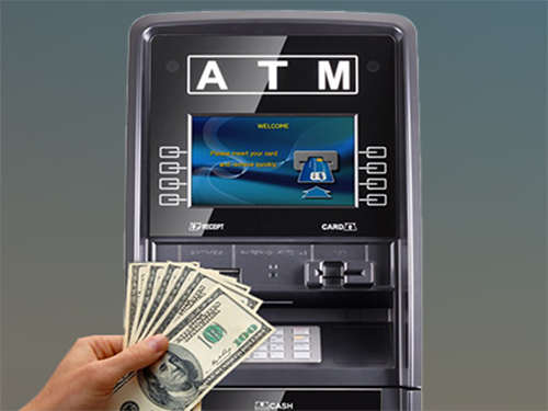 Hand holding cash in front of a black ATM machine screen showing welcome message for ATM machine sales.